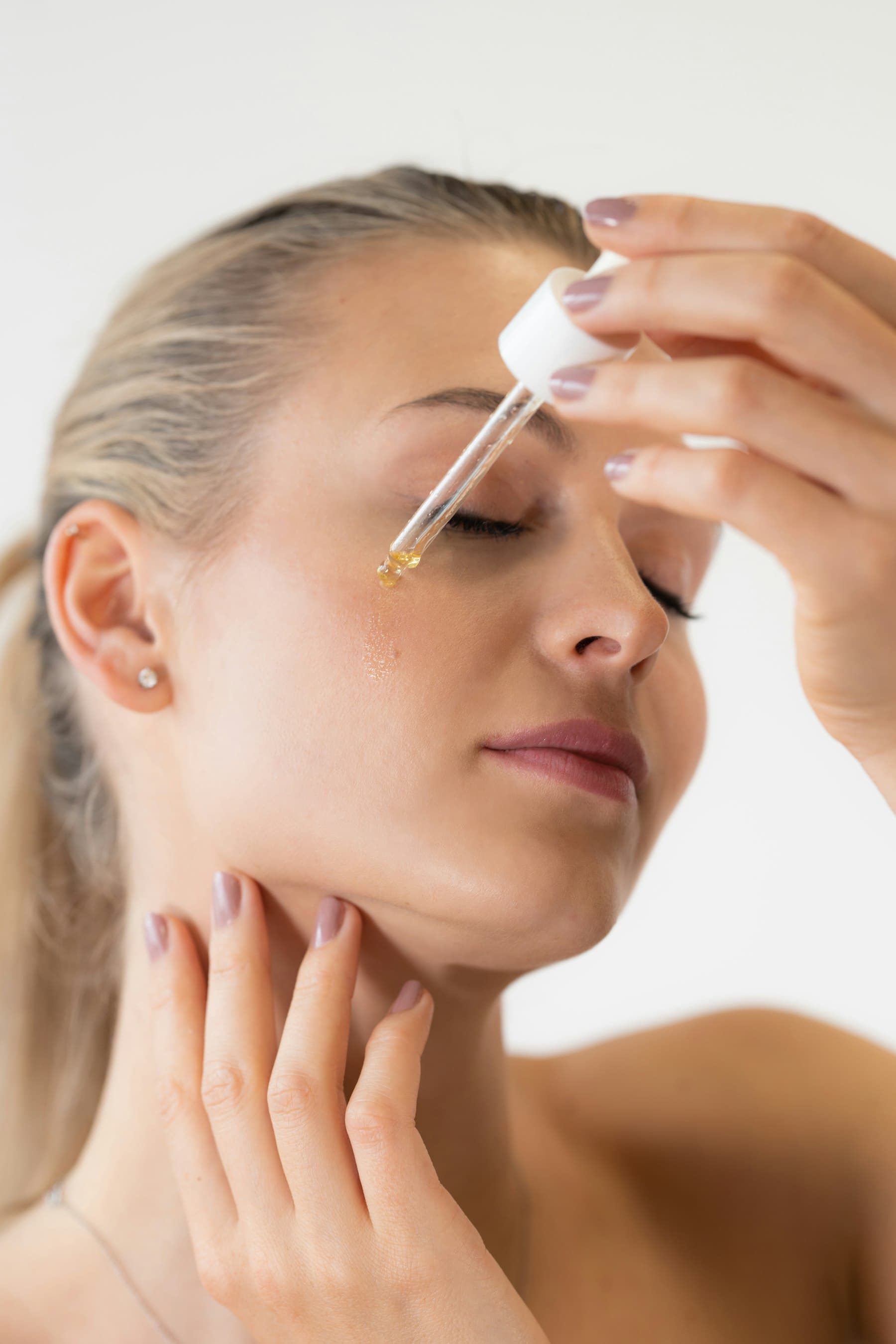 Applying oil with a dropper to the face